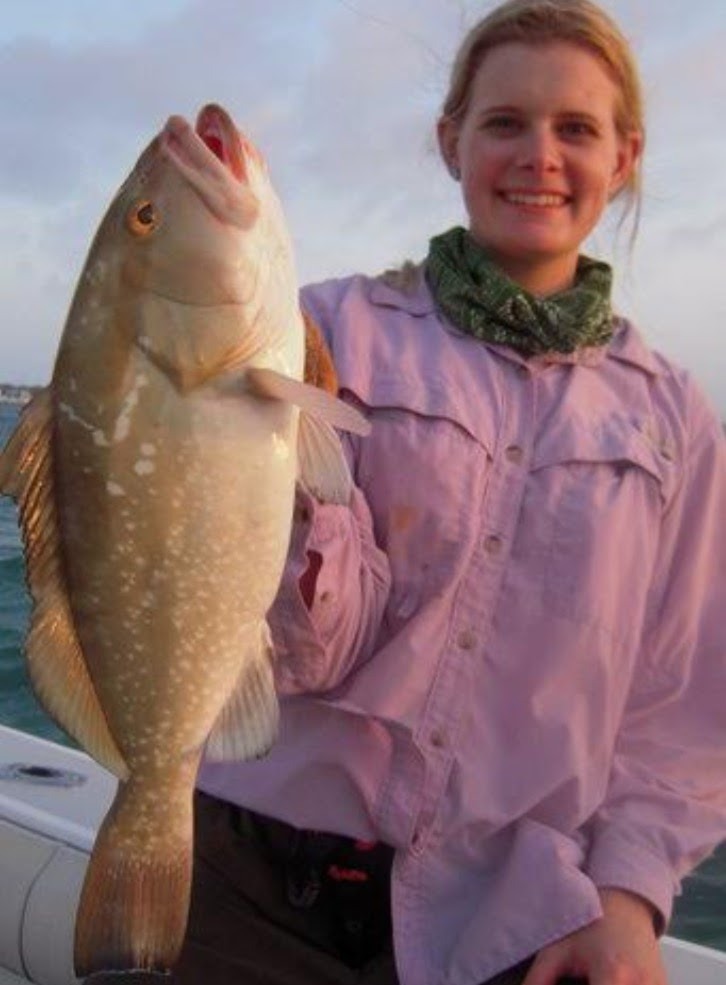 An angler in a purple shirt with her catch
