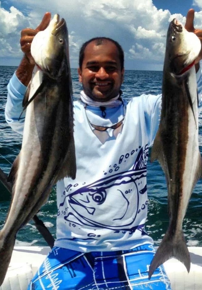An angler holding two fish at sea